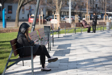 Woman sitting on a bench in the park and use her phone