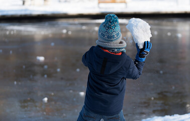 Little boy play with snow in the park a winters day
