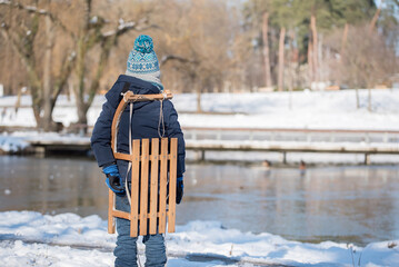 Child with a wooden sled in park a winters day