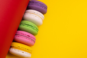 Traditional french multicolored macaroons falling on yellow  background