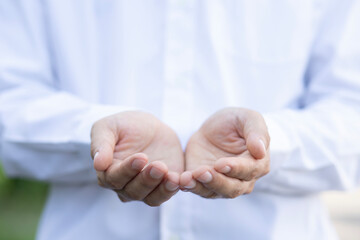 Close-up shot of a man wearing a white long-sleeved shirt. who opens both hands to support...
