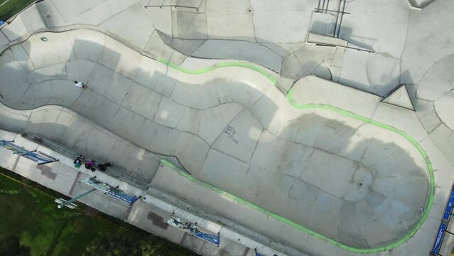 Topdown footage of a skatepark. Drone flies down while turning left. A single person skates in the pool. Recorded in 4k quality. Location in San Borja district of Lima, Peru.