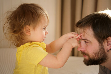 Happy Father with Daughter, Tiny Girl. One Year Baby Smiling, Laughing, Looking up at Daddy. Man Showing Affection to Child. Candid Real Emotion. Beard Dad and Little Kid. Authentic Family Lifestyle.