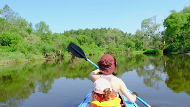 Family kayak trip. Mom and daughter rowing a boat on the river, a water hike, a summer adventure. Eco-friendly and extreme tourism, active and healthy lifestyle