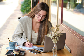 Entrepreneur working with a notebook and a laptop in a coffee shop. Digital nomad.
