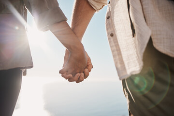 Love, unity and couple holding hands on the beach while on a date for romance or their anniversary....