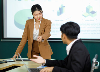 Millennial Asian happy professional successful female businesswoman presenter trainer standing presenting business ideas strategy graphs charts on monitor in meeting room.