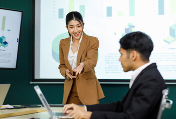 Millennial Asian happy professional successful female businesswoman presenter trainer standing presenting business ideas strategy graphs charts on monitor in meeting room.