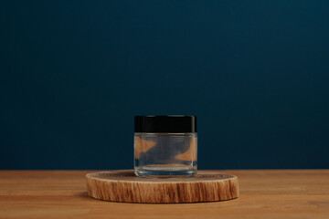 Glass jar on wooden stage and navy blue background. Product presentation. Template.