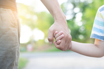 Father's hand leads his son in the park summer outdoor nature family trust concept