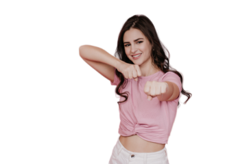 Fit brunette young woman in pink t-shirt and white pants practicing box, with clenched fists, looking at camera, toothy smiling over transparent backdrop with copy space. Sport, fitness, healthcare.