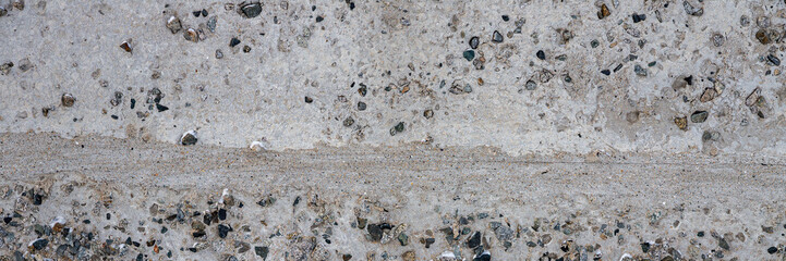 The texture of the old concrete wall. A rough gray concrete surface with many small pebbles. Wide panoramic texture for background and design.