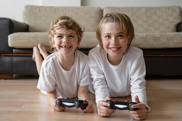 Cute children joyful playing video games with controller console, brother sister expressing...