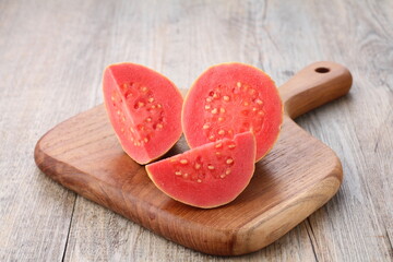 slices of red guava on a wooden cutting board on the dining table