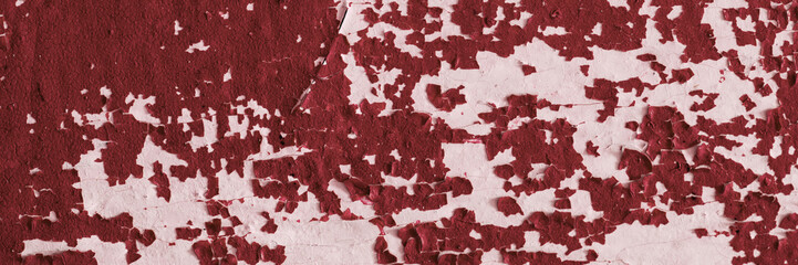 Peeling paint on the wall. Panorama of a concrete wall with old cracked flaking paint. Weathered rough painted surface with patterns of cracks and peeling. Wide panoramic texture for design background