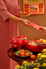 Giving red lucky money envelopes to each other. Asia's customary holiday. Front view. Young women wearing Vietnamese traditional costumes give lucky money on Lunar New Year's Day