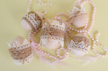 Easter eggs wooden, decorated with lace and braid close-up on a light yellow background. Handmade rustic style
