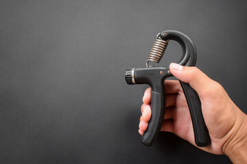 Hand exercising, squeezing a handgrip, man gripping hand exercise gripper.