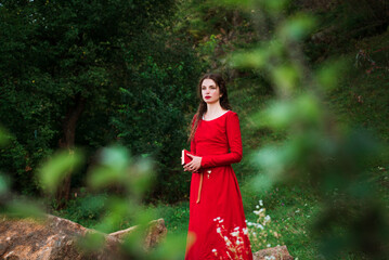 Vintage portrait of a beautiful noble lady in a red dress with a book in the garden 1