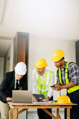 Two colleagues discussing data working and tablet, laptop with on on architectural project at construction site at desk in office.