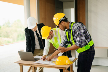 Two colleagues discussing data working and tablet, laptop with on on architectural project at construction site at desk in office.