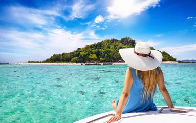 Zelfklevend Fotobehang A beautiful tourist woman with sunhat sits on a yacht and looks at the turquoise sea and beaches of Bamboo island in the Krabi region, Thailand © moofushi