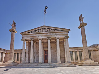 Obraz premium Front facade of the national academy with Athena and Apollo gods on Ionian columns and other ancient Greek gods and deities on the pediment. Cultural travel to Athens, Greece.