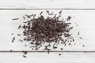 Heap of black tea on white wooden table