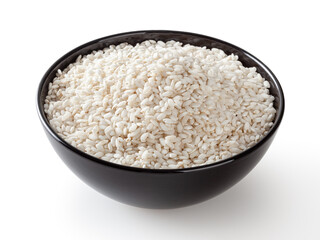 Uncooked arborio rice in black ceramic bowl isolated on white background with clipping path