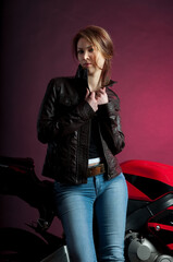 Fototapeta na wymiar Sensual woman, fashion model in jeans and leather jacket stands near motorbike