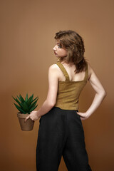 woman with stylish hairstyle posing with plant in pot