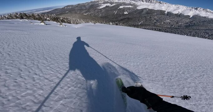 pov powder skiing in pristine fresh snow with blue sky and rocky mountains in the background