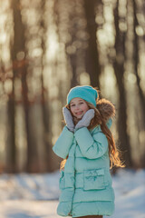 girl in a turquoise squat and a hat in a winter forest, shot vertically