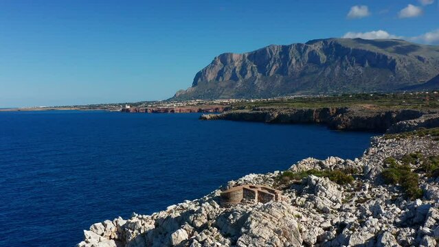 Rocky cliff above the sea in Terrasini, Sicily, Italy. Sea and blue sky and mountains on the horizon. Aerial shot.