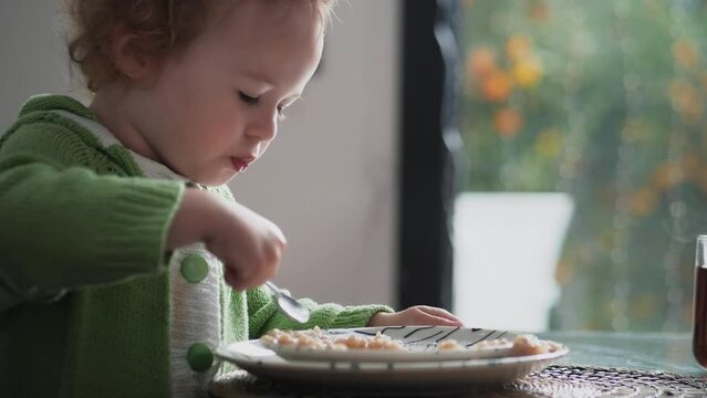 Little girl having oatmeal or porridge for breakfast at home. Healthy eating