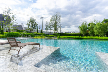 Wooden daybed place on tile floor in swimming pool with blue sky.