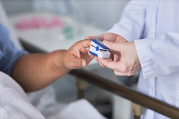 Minimal closeup of nurse measuring oxygen saturation of senior female patient in hospital