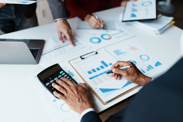 Team business adviser meeting to analyze and discuss the situation on the financial report n the meeting room with using calculator, documents, computer laptop in work.