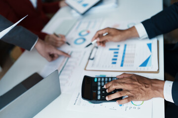 Team business adviser meeting to analyze and discuss the situation on the financial report n the meeting room with using calculator, documents, computer laptop in work.