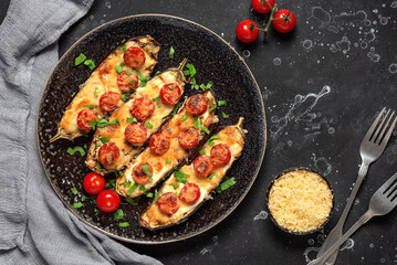 Baked eggplants with cherry tomato and cheese on a black background. Top view, flat lay, copy space.