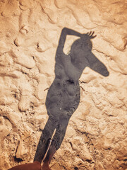 The shadow of the girl falls on the sand
