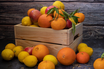 Freshly picked lemons, oranges, tangerines and apples in a Wooden Case.