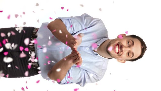 VERTICAL VIDEO POV happy man blowing heart shape flying confetti romantic holiday posing isolated