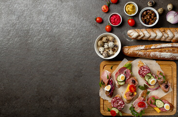 Sandwiches on a dark background, or assorted canapes or pintxos, tapas. Copy space. Concept party food or blog ingredient.