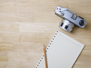 Notebook and camera on wooden texture background