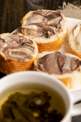Green tea brewed in a mug and a baguette with chocolate butter