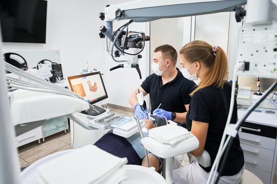 Dentist scanning patient's teeth with modern machine for intraoral scanning. Digital print of patient's teeth is on big screen. Modern high precision technologies. Concept of modern dentistry