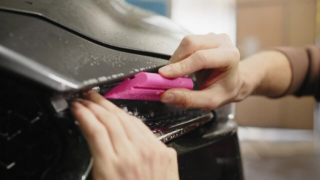Close up to PPF installation process on a front headlight . PPF is a paint protection film which protect paint from scratches and stone chips. Concept of: guard, protect, car, new, work