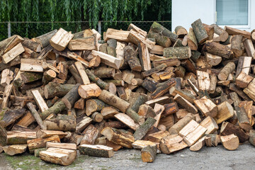 A pile of firewood for heating in winter in the yard of the farm