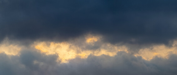Dark storm clouds illuminated by the bright evening sun, panorama